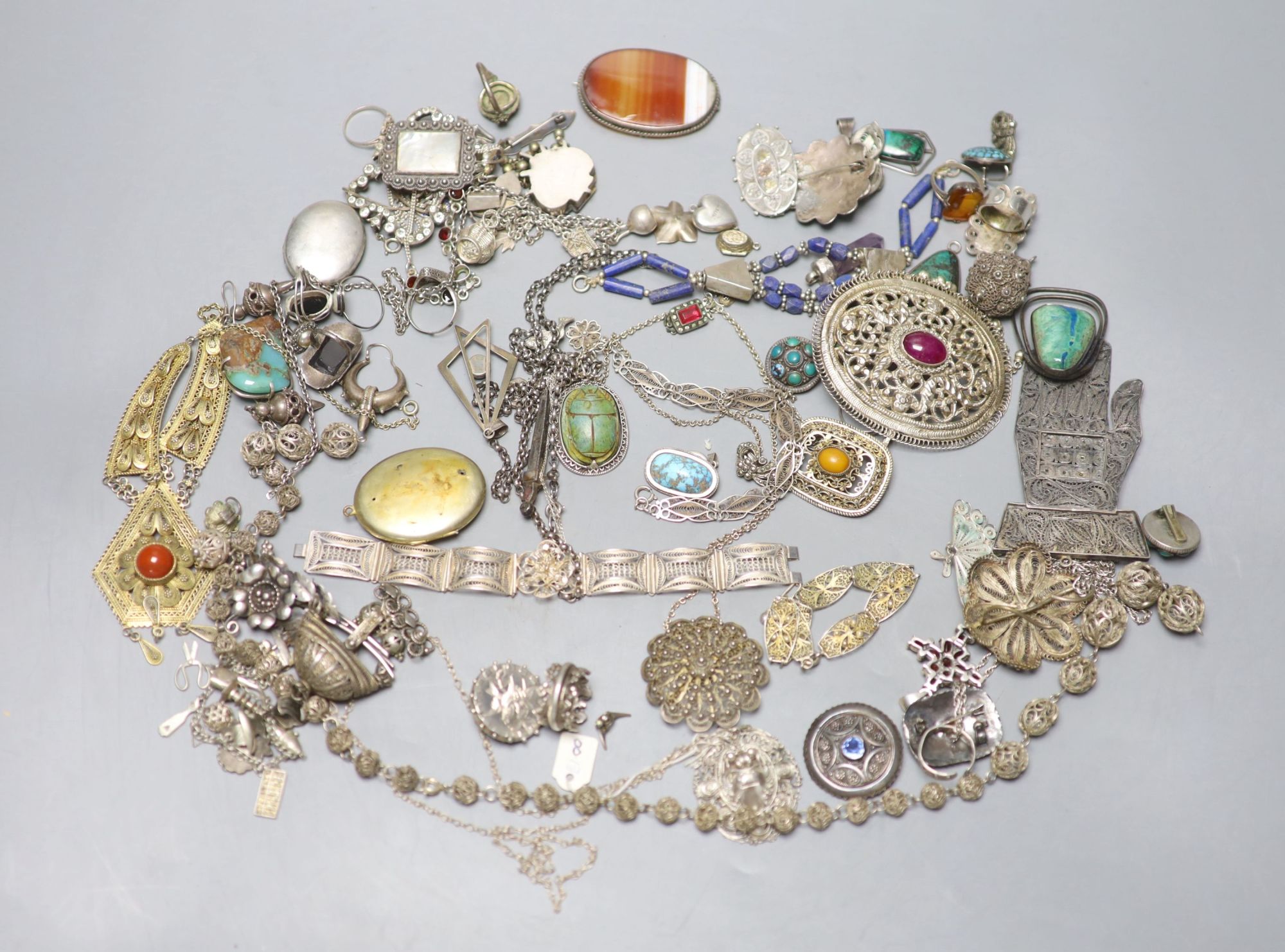 A mixed group of assorted white metal and costume jewellery including locket, brooches and filligree items.